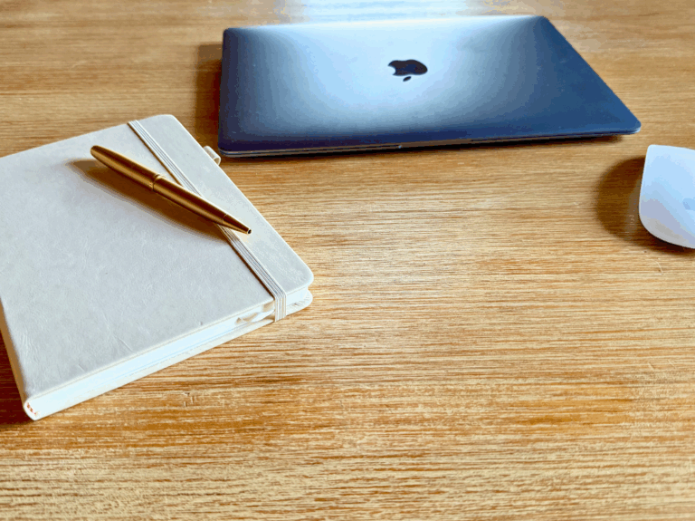 SEO-Texte schreiben lassen: Notizbuch und MacBook auf dem Holztisch